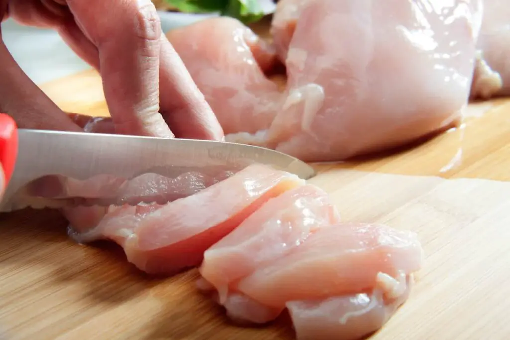 A man cutting raw chicken.